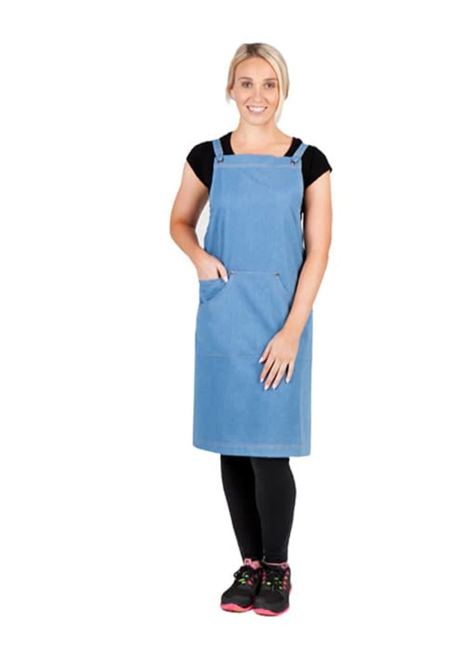 A model wearing a blue denim apron with straps, featuring a front pocket, paired with black leggings and shoes.