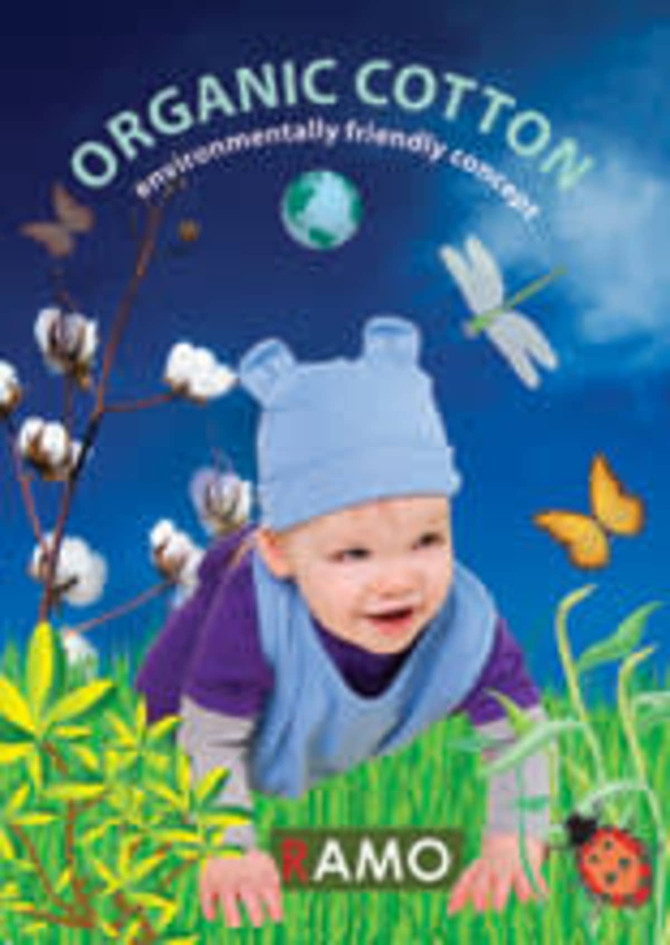 A promotional image showcasing a baby wearing a blue organic cotton bib amidst a vibrant nature background with butterflies and cotton plants.
