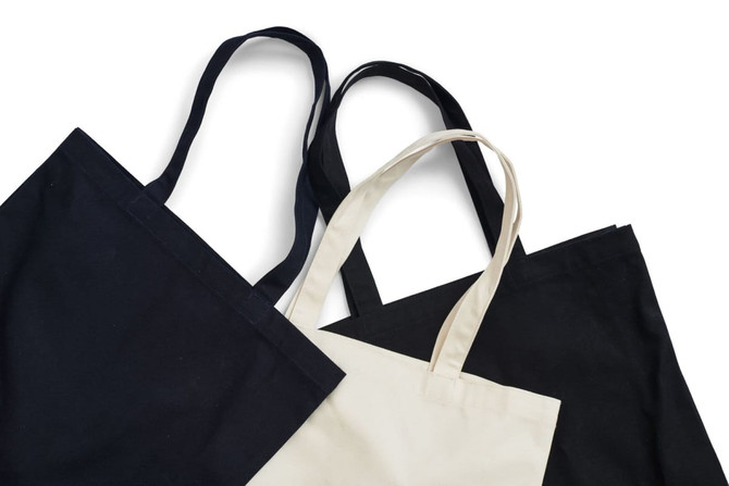 A set of heavy tote bags in black, cream, and beige, featuring sturdy straps and a simple design.