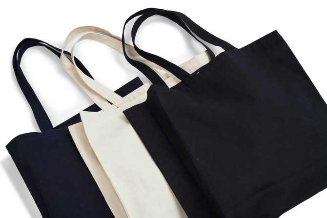 A set of three tote bags in black and cream, featuring sturdy handles and a simple design. One bag is smaller than the others.