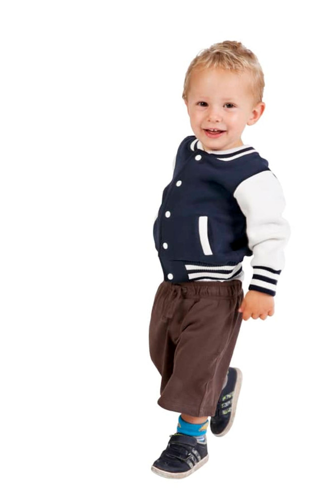 A child wearing a navy and white varsity jacket with striped cuffs, paired with brown shorts and sneakers.