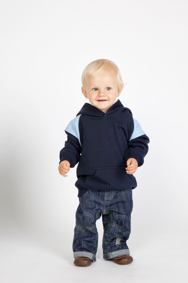 A toddler in a navy hoodie with light blue contrast panels, paired with denim jeans and brown shoes.
