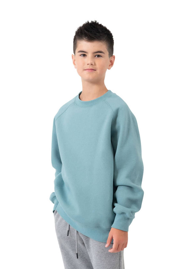 A child wearing a light blue cotton sweatshirt with long sleeves, paired with grey sweatpants.