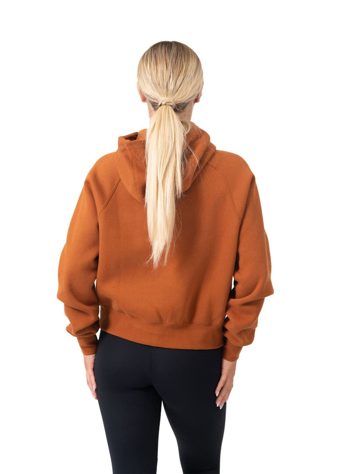 A women's half-zip jumper in burnt orange, featuring a hood and a relaxed fit, seen from the back.