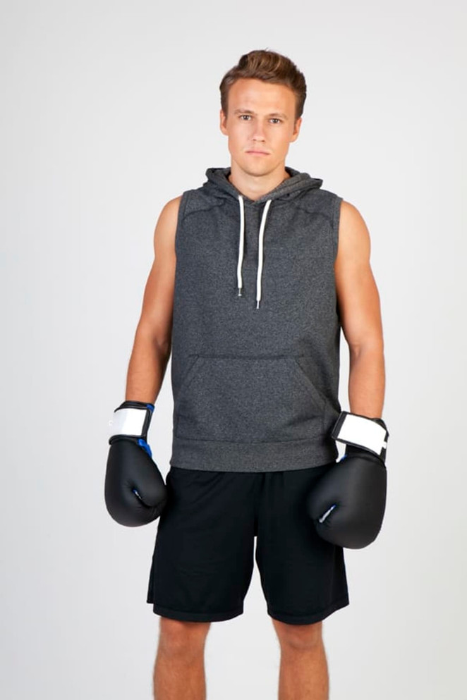 A sleeveless grey hoodie is worn by a male model, paired with black boxing gloves and shorts against a plain background.