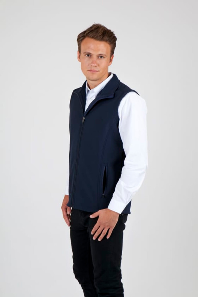 A man wearing a navy soft shell vest with a zip and side pockets, set against a plain background.