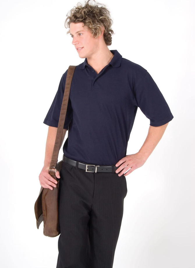 A man in a navy blue polo shirt poses with a brown messenger bag, wearing black trousers and a belt.