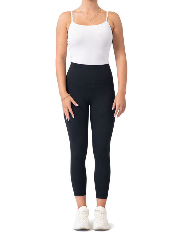High rise full-length leggings in black, paired with a white tank top and white sneakers. Features a logo on the waistband.