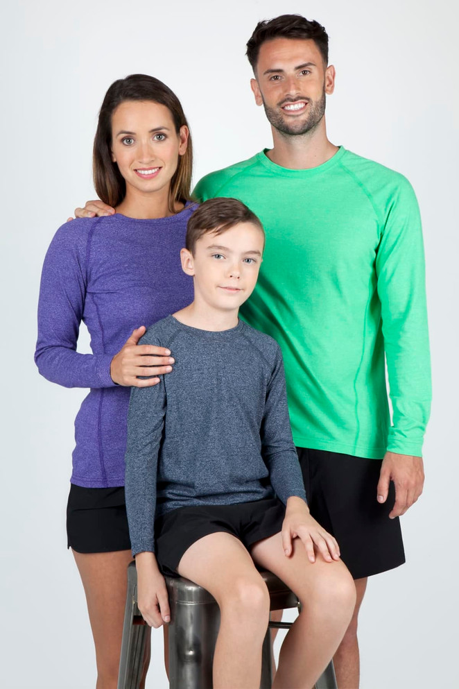 A purple long sleeve T-shirt on a woman, a green one on a man, and a grey one on a boy, all smiling.