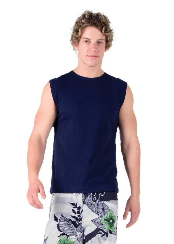 A man in a navy muscle T-shirt and patterned shorts stands on green grass, with trees in the background.