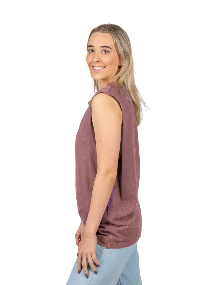 A woman models a stone-washed tank top in a soft mauve hue, featuring a relaxed fit and sleeveless design.