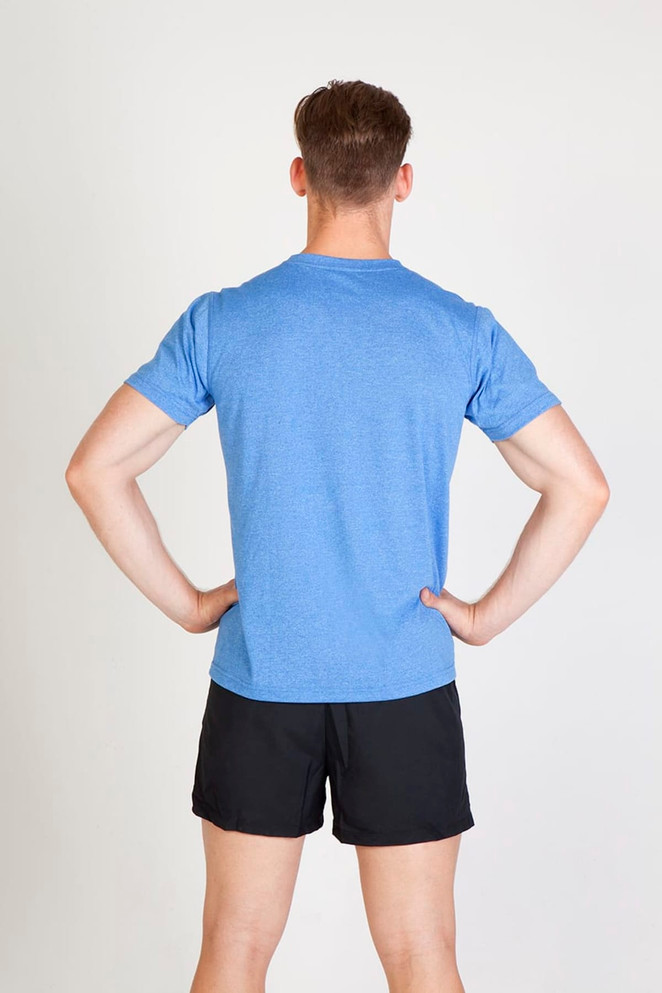 A man wearing a blue heather t-shirt and black shorts, standing with his hands on his hips.