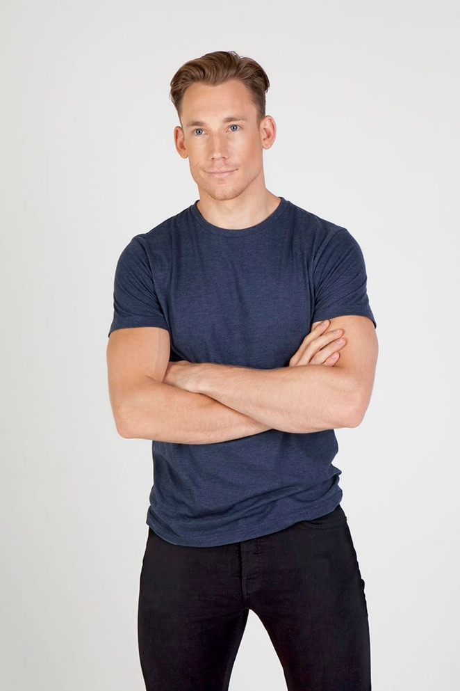A navy crew neck T-shirt, made from marl fabric, displayed on a male model with casual black pants.