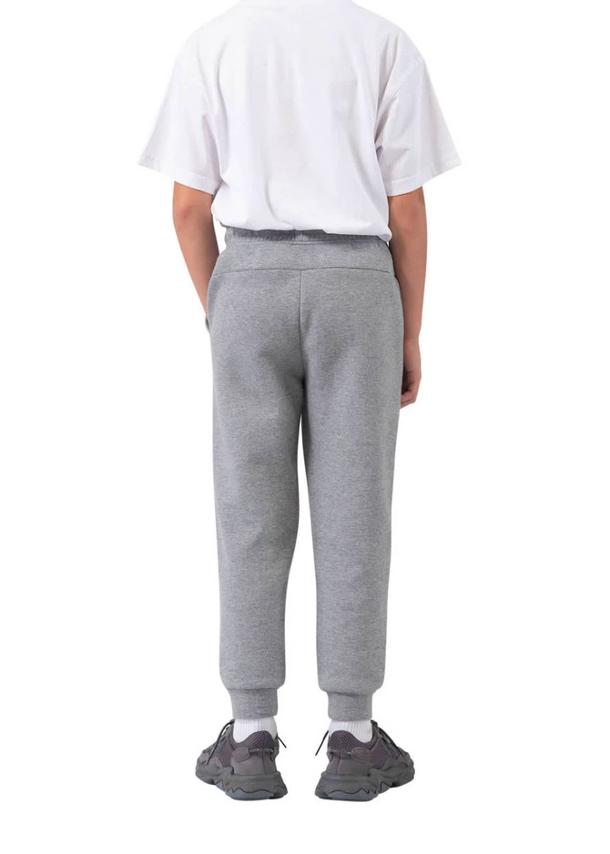 Three-layer cotton track pants in grey, featuring a relaxed fit and side pockets, paired with a white t-shirt and sporty shoes.