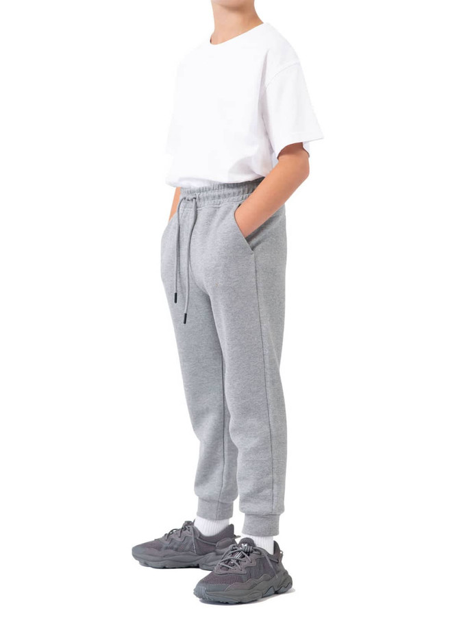 A pair of grey three-layer cotton track pants with side pockets, modelled by a person wearing a white t-shirt and sneakers.