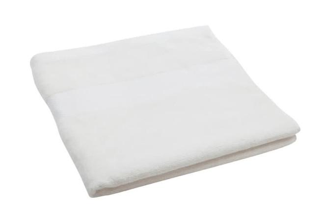 A folded white bath towel with a textured surface, featuring a logo on one corner.