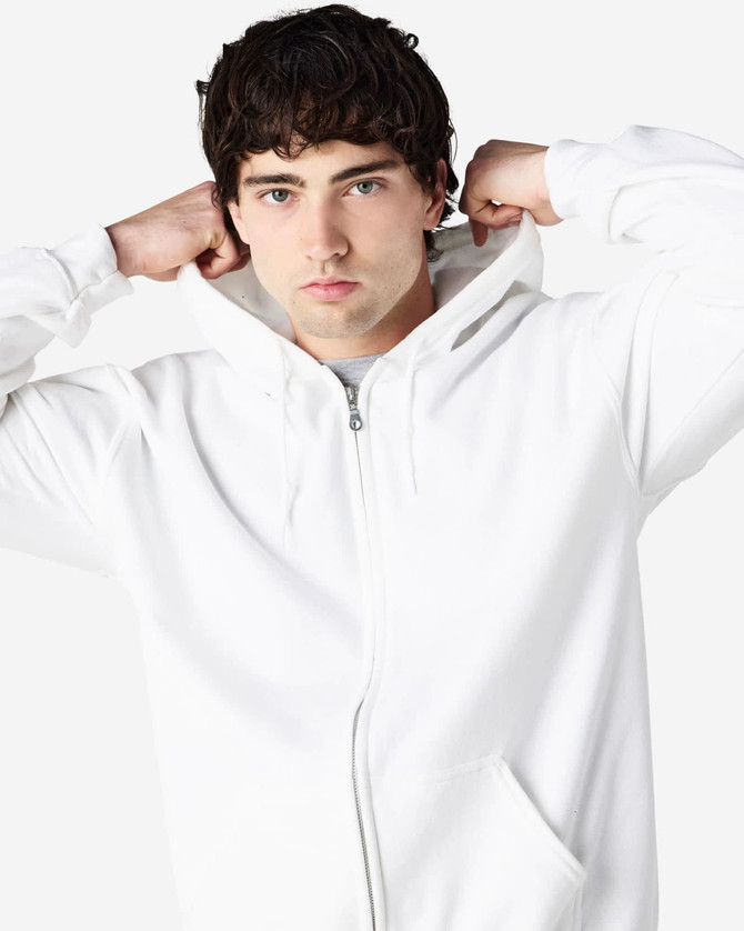 A white Gildan Heavy Blend adult full zip hooded sweatshirt worn by a model adjusting the hood.