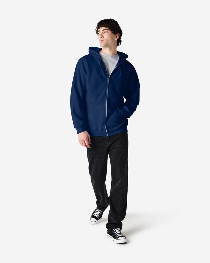 A model is wearing a navy blue Gildan Heavy Blend adult full zip hooded sweatshirt with black pants and sneakers.