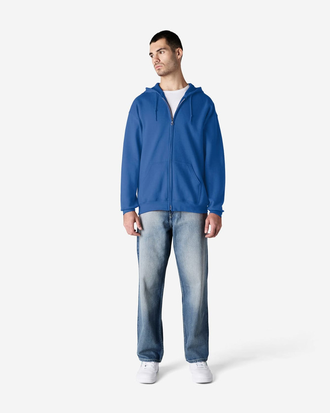 A blue Gildan Heavy Blend adult full zip hooded sweatshirt on a model, paired with light jeans and white shoes.