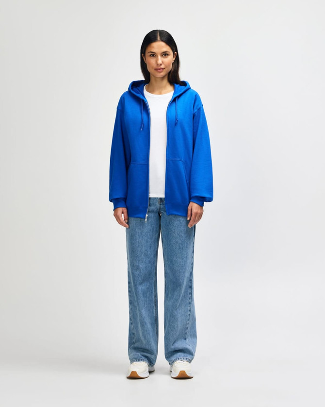 A blue Gildan Heavy Blend adult full zip hooded sweatshirt on a model, paired with light jeans and white shoes.