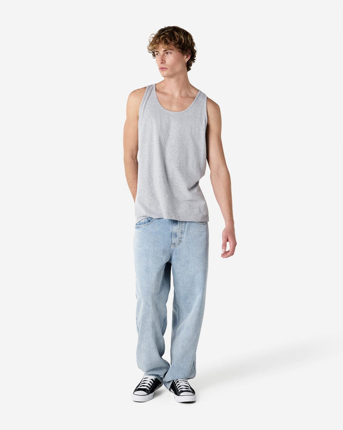 A unisex fine jersey tank in grey, paired with loose-fitting light blue jeans and black shoes. Features a logo.