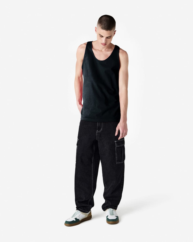 A black unisex fine jersey tank top worn with baggy black pants and sneakers, featuring a visible logo.