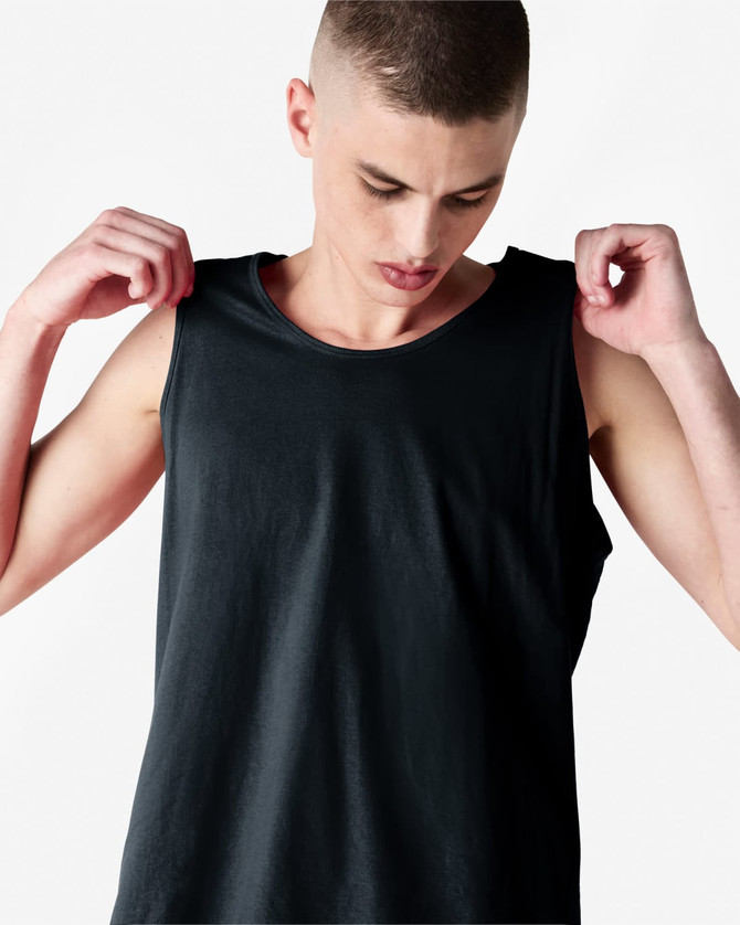 A black unisex fine jersey tank top being worn by a model, featuring a logo on the fabric.