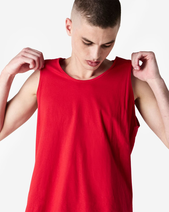 A red unisex fine jersey tank top with a relaxed fit and logo. Model is adjusting the straps.