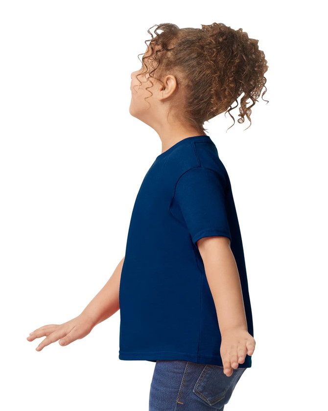 A toddler wearing a side-view navy blue Gildan Heavy Cotton T-Shirt with a plain design.