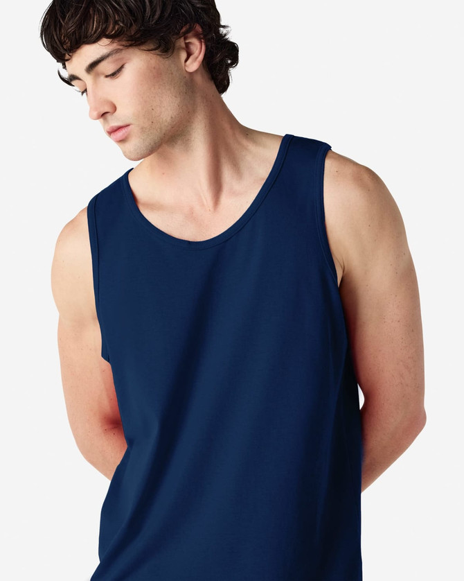 A navy blue Gildan Heavy Cotton adult tank top on a model, featuring a logo.