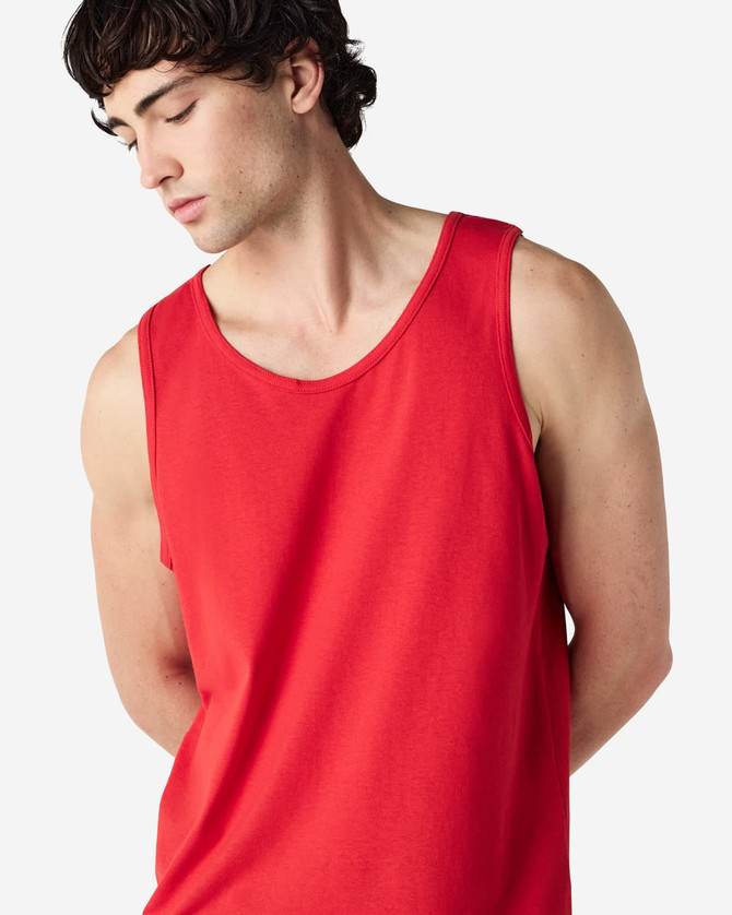 A red Gildan Heavy Cotton adult tank top displayed on a model with short, curly hair and a neutral background.