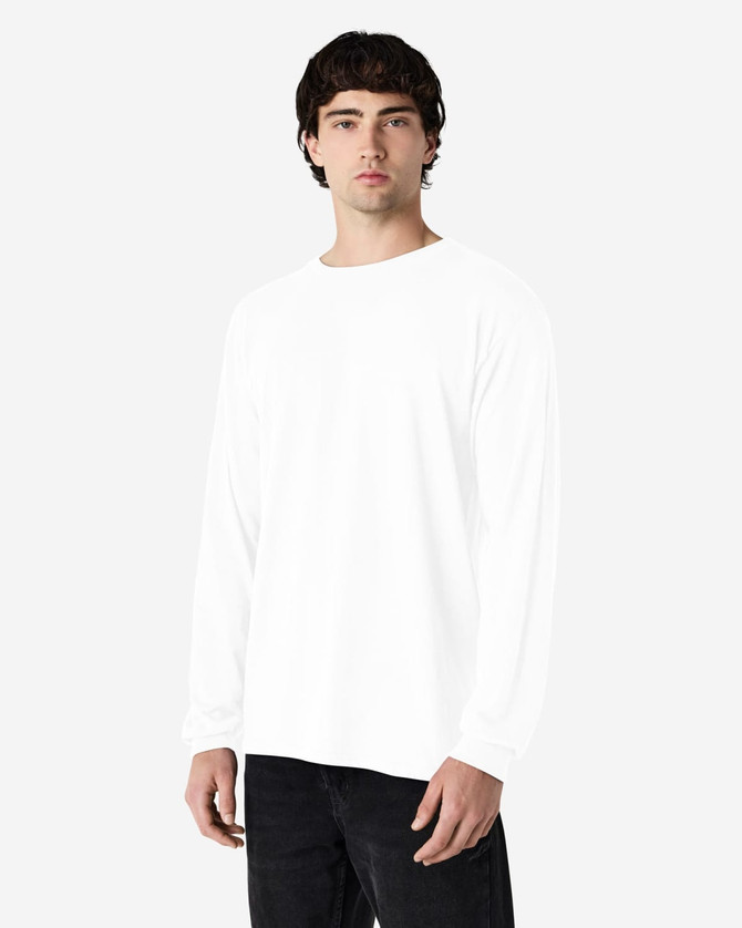 A model wearing a white long sleeve T-shirt with a simple design, paired with black jeans.