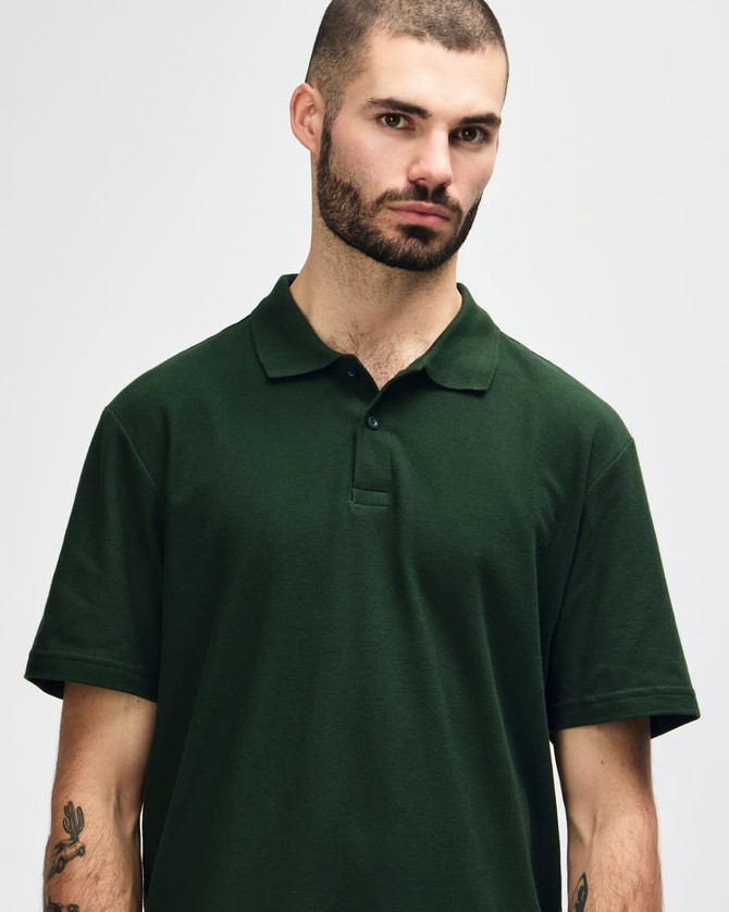 A model wearing a dark green Gildan Softstyle Adult Double Pique Polo with a three-button placket and collar.