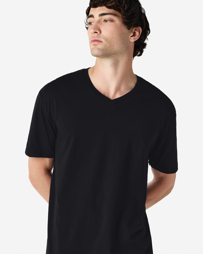 A black Gildan Softstyle adult v-neck t-shirt worn by a model standing with hands behind their back.