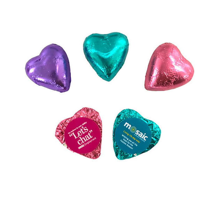 A selection of heart-shaped chocolates in purple, teal, and pink foil, with some featuring branding.