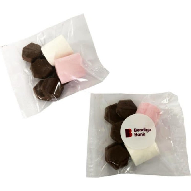 A clear bag containing dark chocolate pieces and pink and white marshmallows, with a logo on the packaging.
