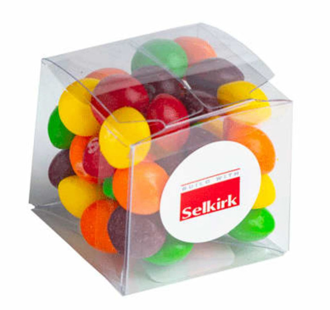 A transparent cube containing a mix of colourful Skittles, featuring yellow, orange, green, red, and purple candies.