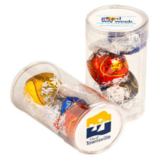 Three Lindt chocolate balls in a clear tube with decorative filler, featuring a logo on the base.