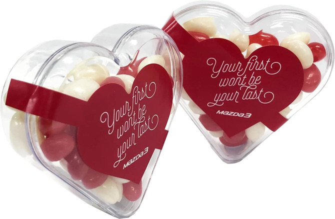 Acrylic heart-shaped container filled with red and white mini jelly beans. It features a logo on the packaging.