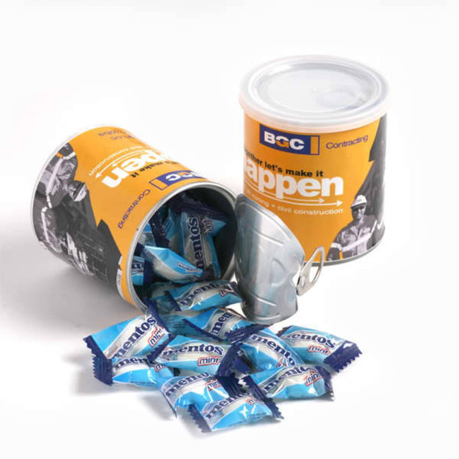 A cylindrical container in orange and white, filled with blue Mentos mints, with some mints spilling out.