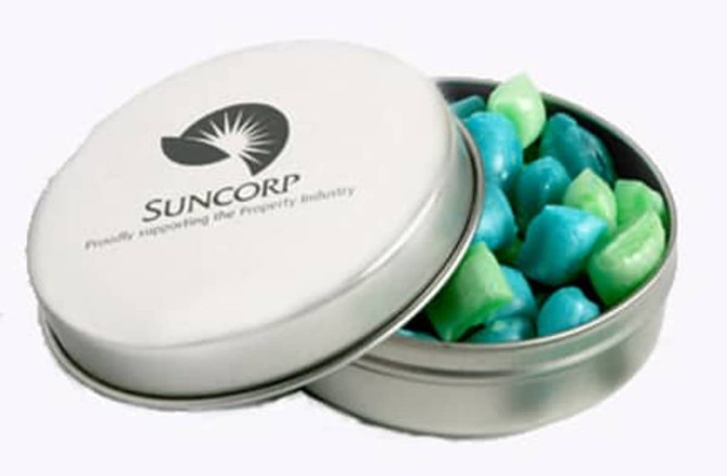 A silver tin containing tiny blue and green humbugs, with a logo on the lid.