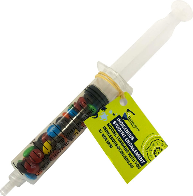 A syringe filled with colourful M&Ms, featuring a branding label attached.