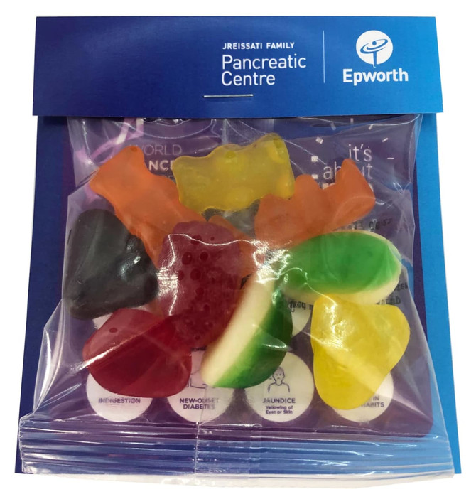 A clear bag containing assorted mixed lollies in various colours, featuring a blue header with a logo.
