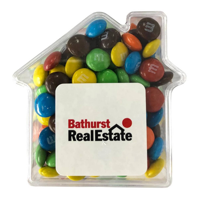 A clear acrylic house filled with colourful M&Ms in various shades of blue, green, red, yellow, and brown.