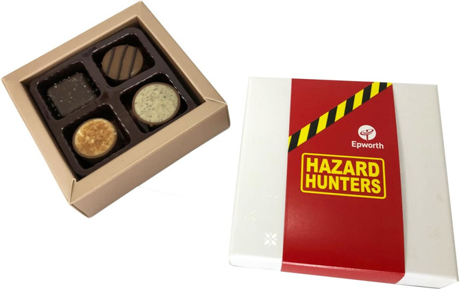A chocolate box with a white and red exterior containing four assorted chocolates in a gold tray inside.