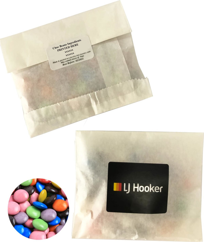 A kraft paper bag containing colourful choc beans, featuring a logo on the front.