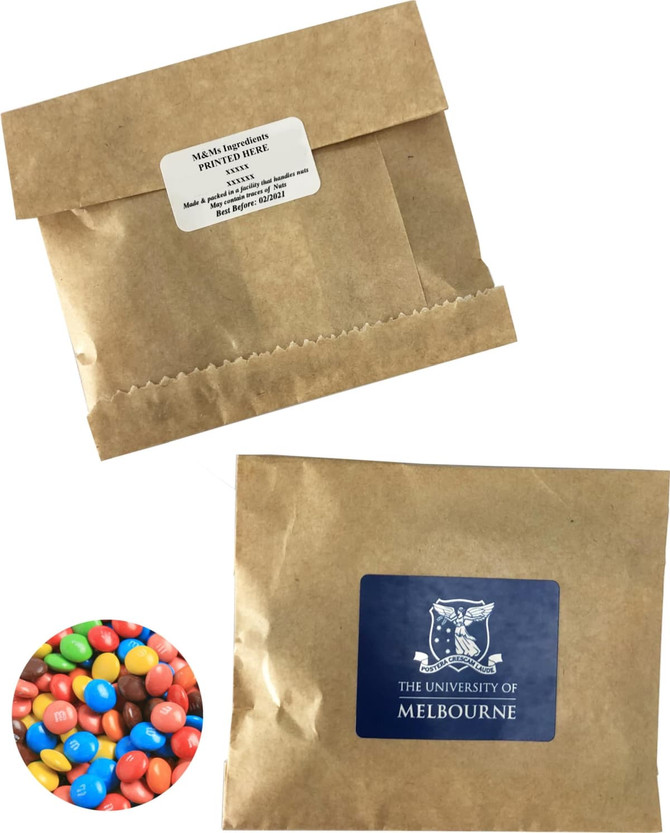 A kraft paper bag containing 50g of multi-coloured M&Ms, featuring a logo on the front.