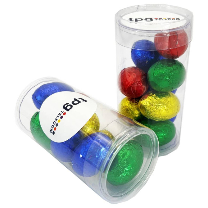 A clear tube filled with colourful foil-wrapped chocolate eggs in blue, green, red, and gold. It features a logo.