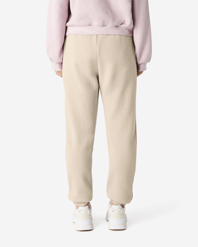 Unisex sweatpants in a beige colour with an elasticised waistband and cuffs, featuring a visible logo.