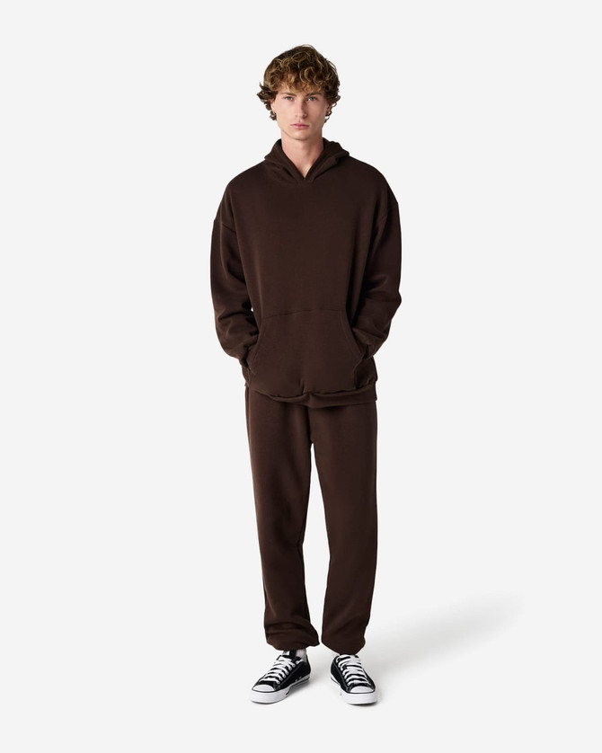 Unisex sweatpants in brown with an elastic waistband; styled with a matching brown hoodie. Features a branding logo.